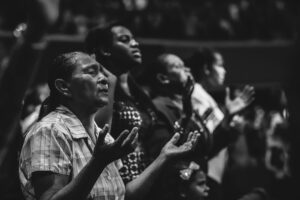 Black and white image of a diverse group of people in prayer during a religious gathering.